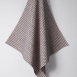 Draped woven outdoor fabric in a subtle stripe design in red and blue on a white wall. 