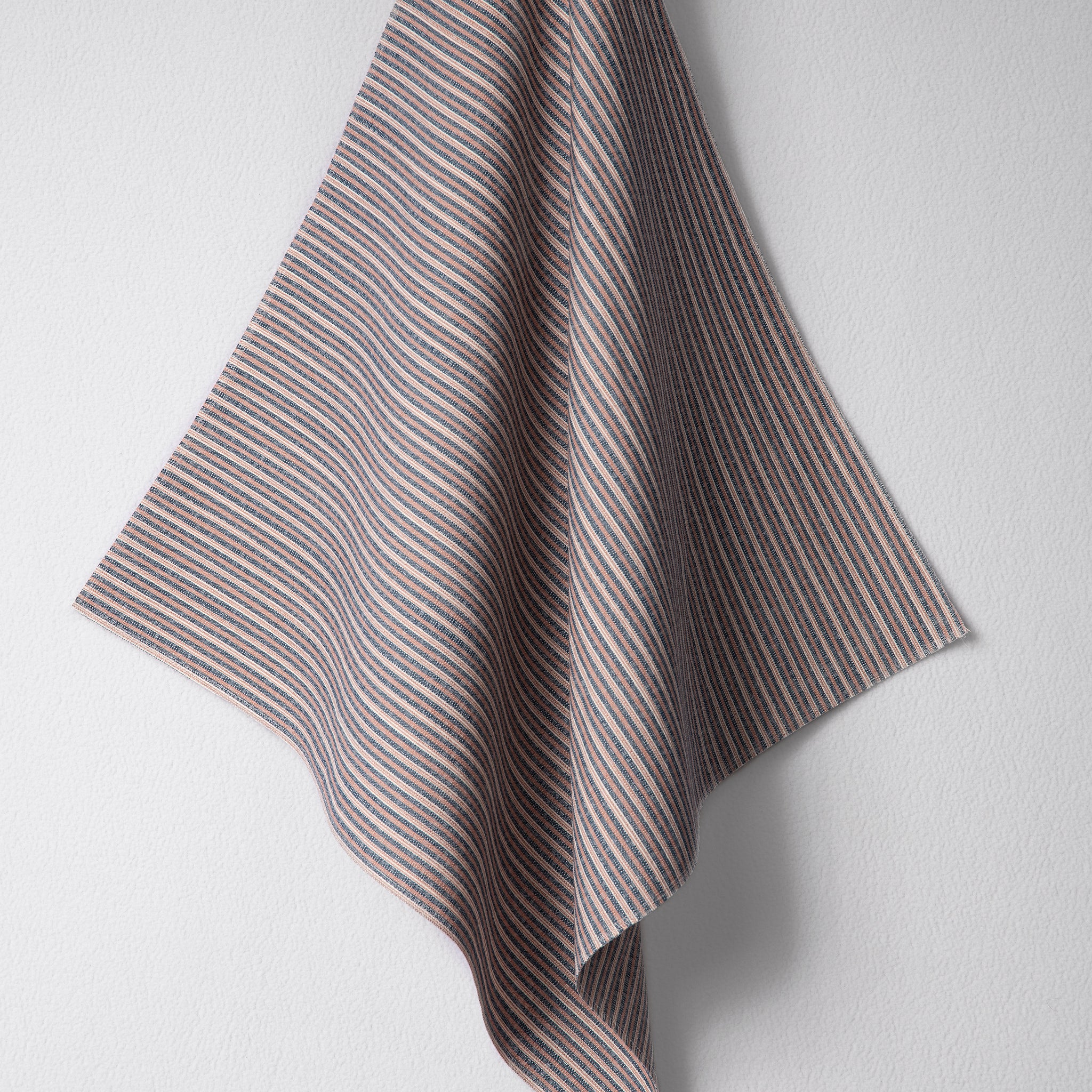 Draped woven outdoor fabric in a subtle stripe design in red and blue on a white wall. 