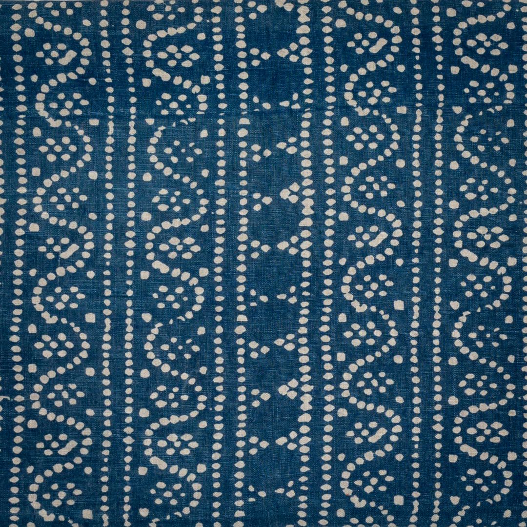 Detail of fabric in a dotted geometric stripe in cream on a navy field.