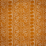 Detail of fabric in a dotted geometric stripe in cream on an ochre field.