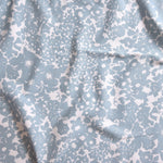 Close up of gently draped woven Indoor-Outdoor fabric with flower and leaf silhouette pattern in light blue on white background