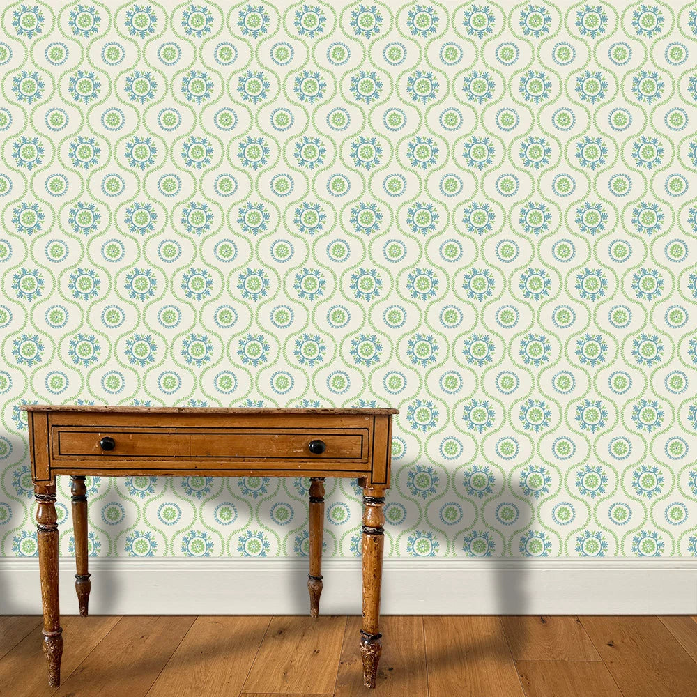 A wooden end table stands in front of a wall papered in a playful floral stripe in blue and green on a light blue field.