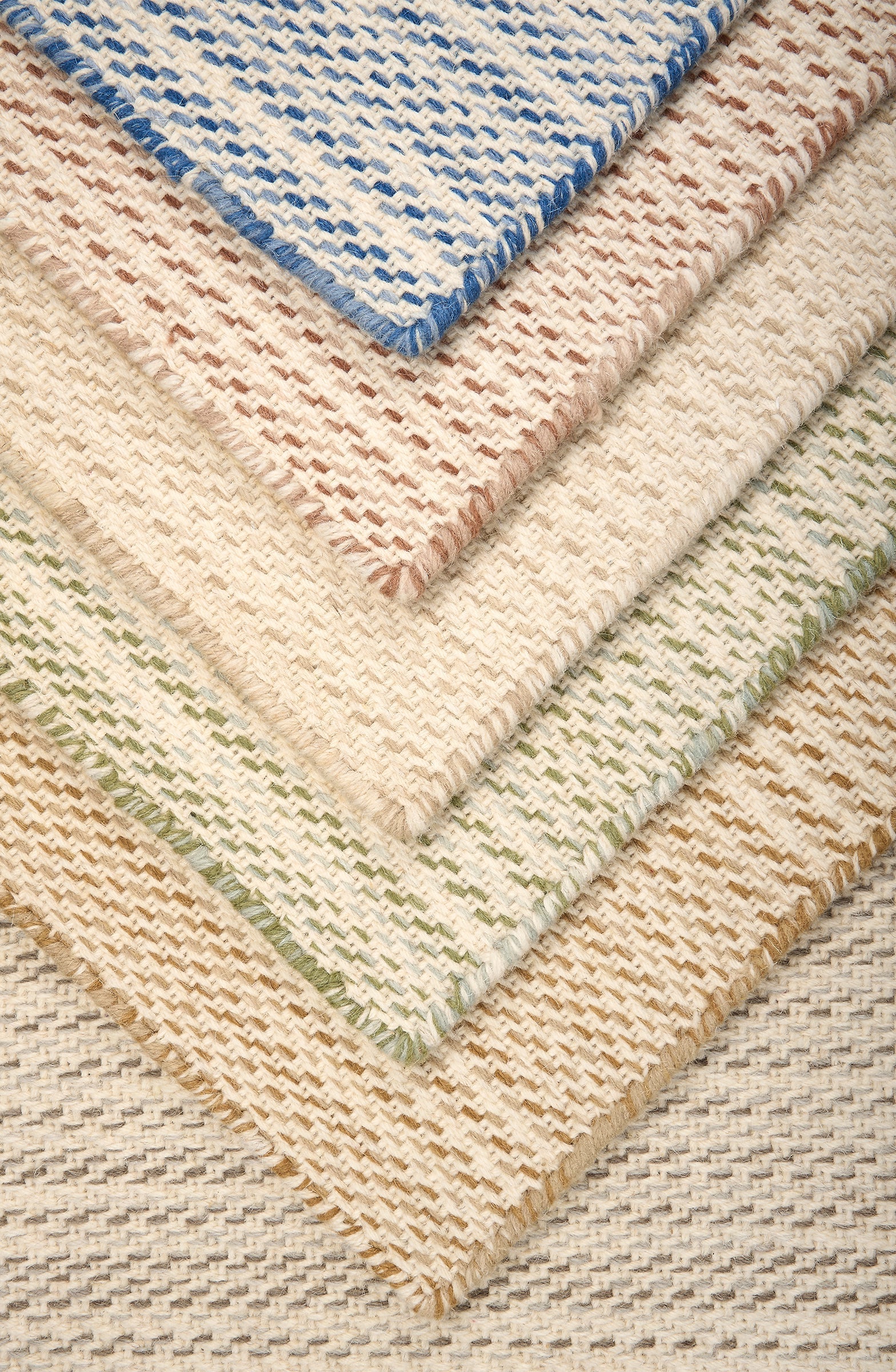 Stack of broadloom carpet samples in a subtle stripe design in taupe, ochre, green, cream, rose red and blue.