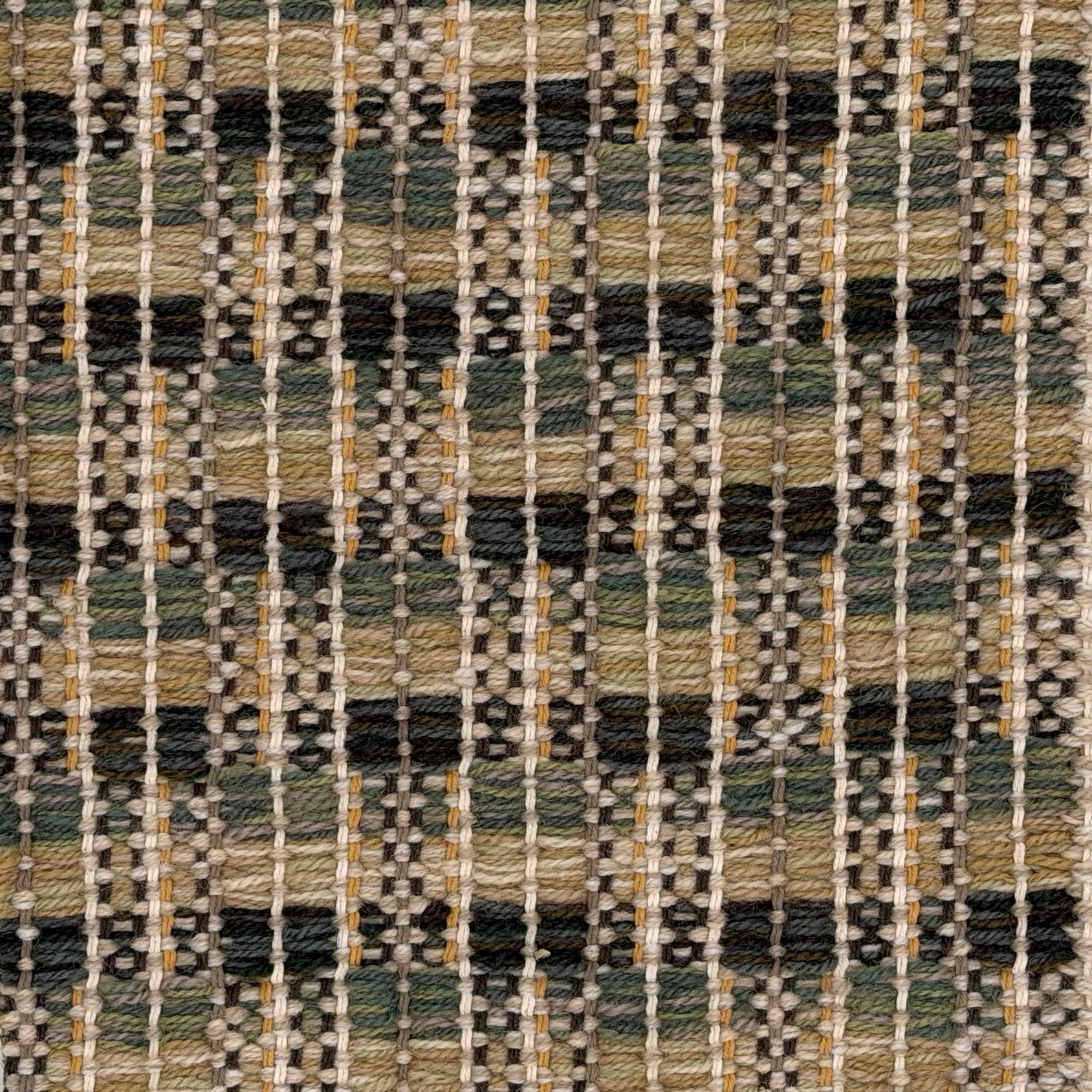 A close-up of a woven rug featuring a checkerboard plaid design with shades of tan, green and brown. 