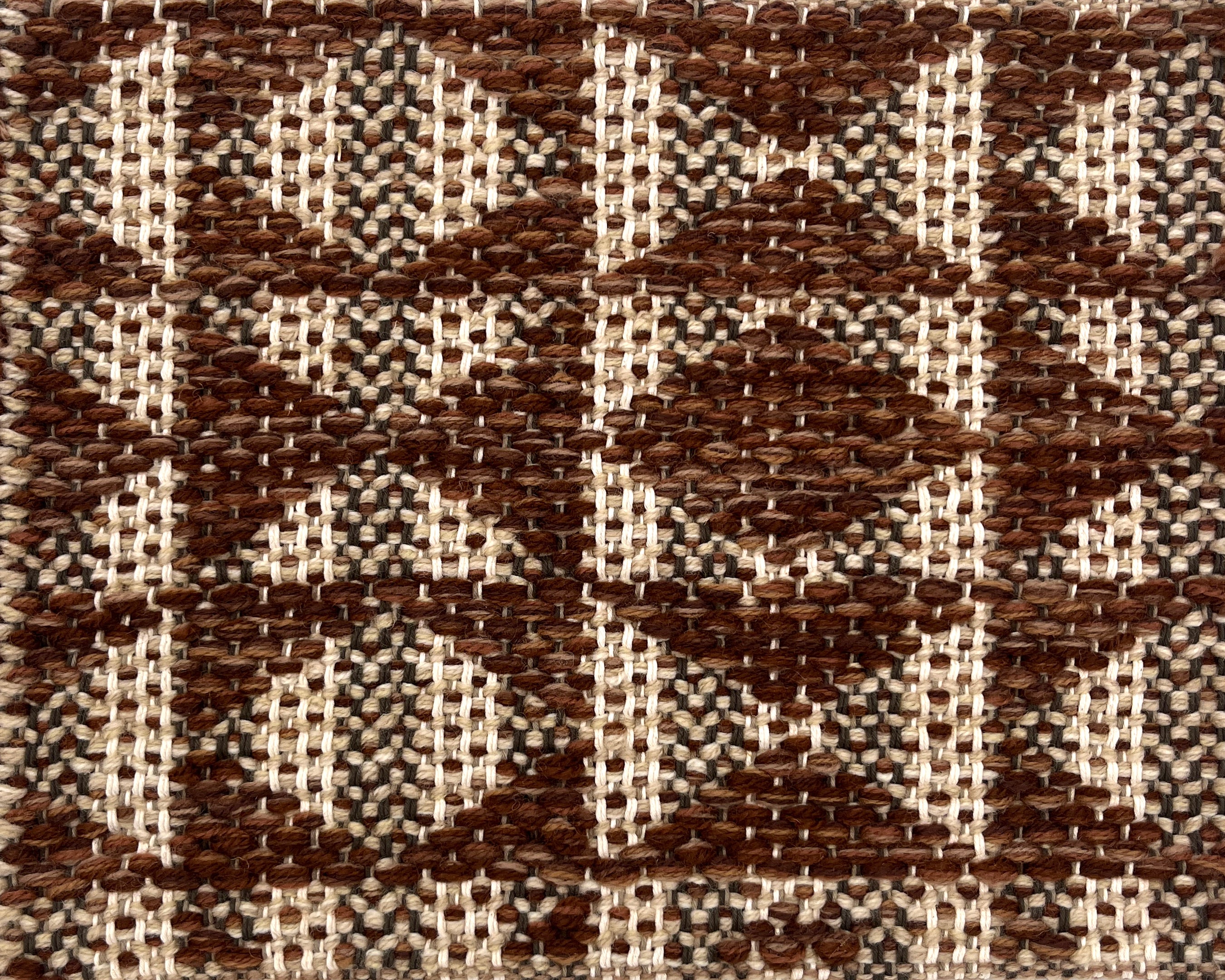 Close-up of a woven rug with geometric pattern in shades of brown.