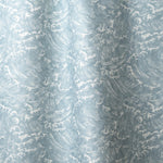 Playful wave print in white on a pastel blue watercolor field.