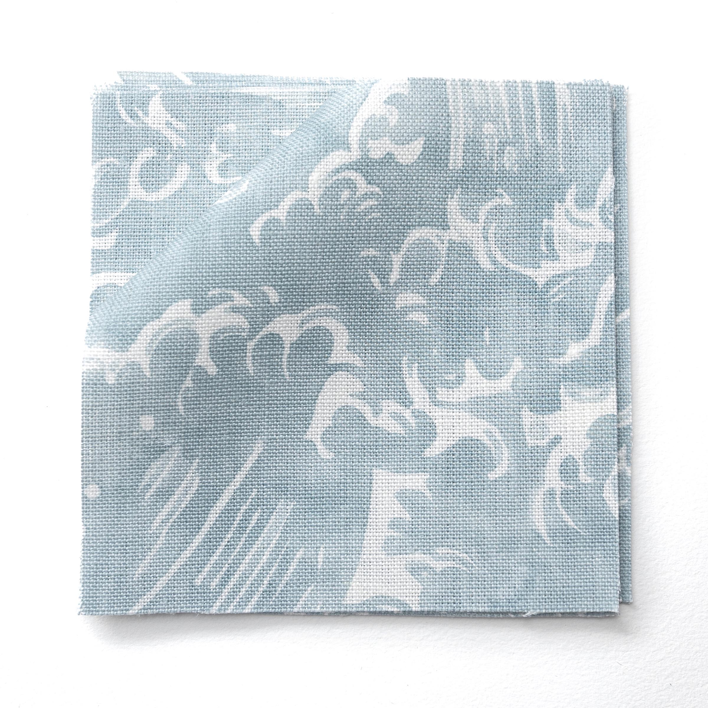 Fabric swatches in a playful wave print in white on a pastel blue watercolor field.