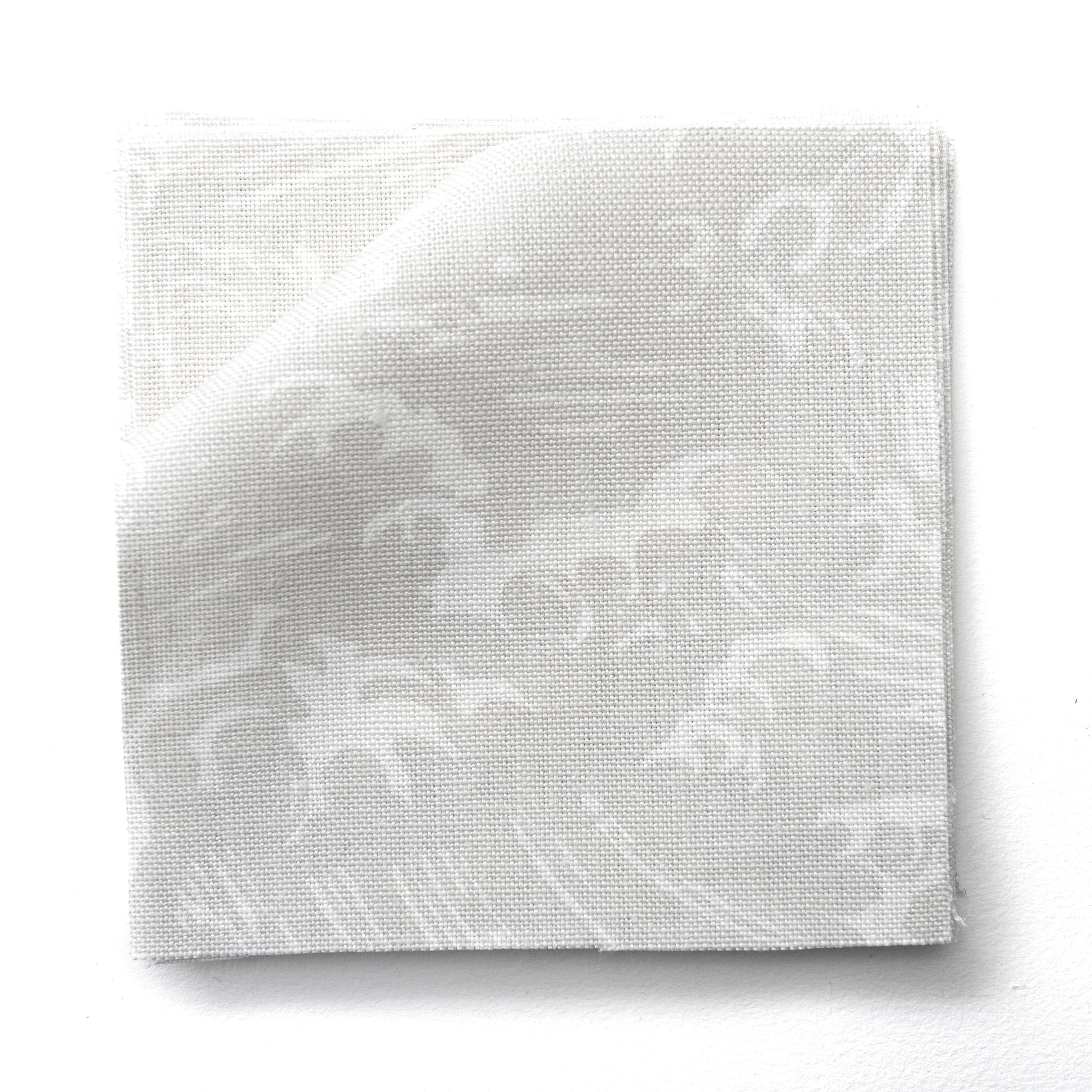 Fabric swatches in a playful wave print in white on a pale grey watercolor field.