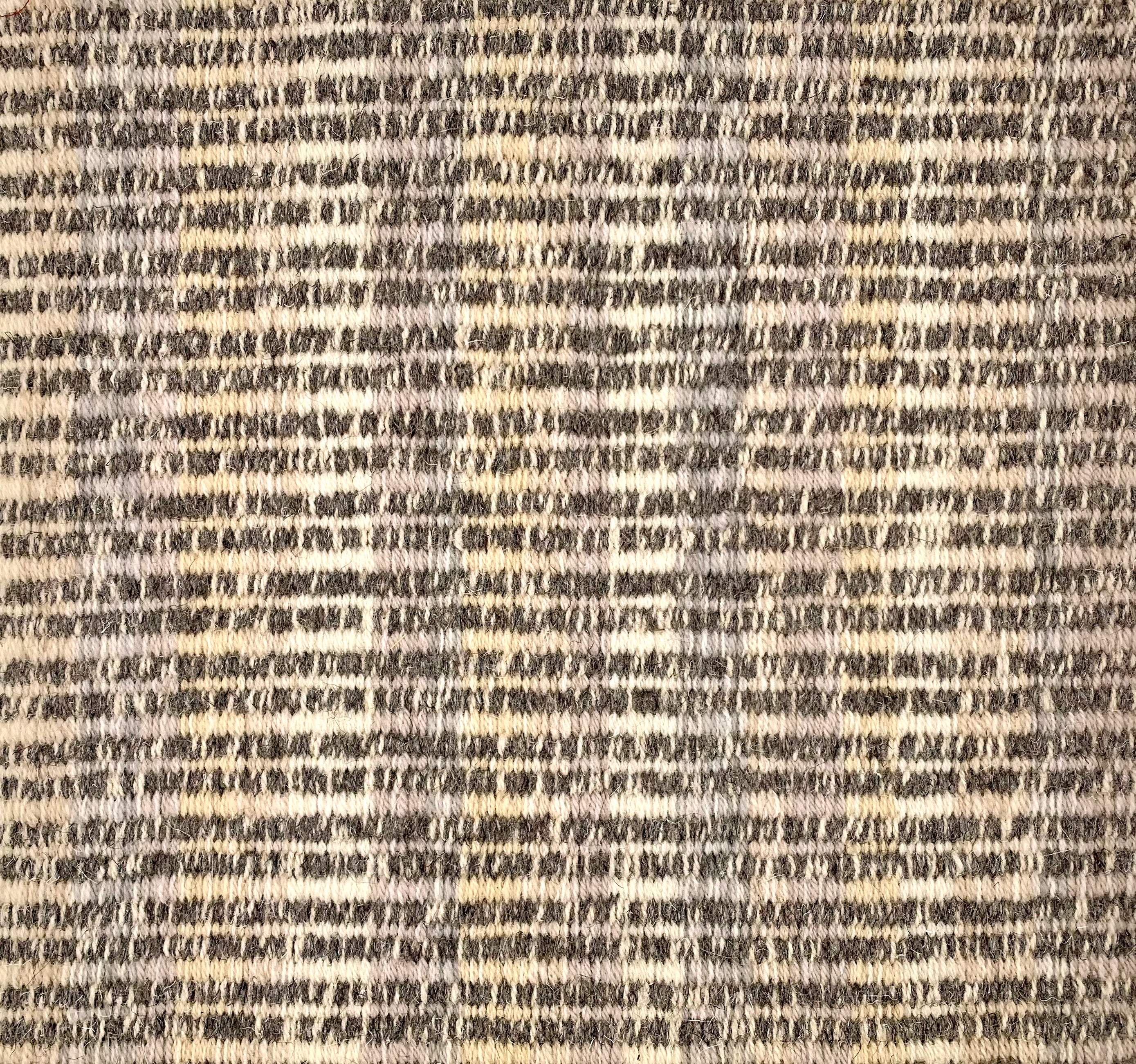 Handwoven rug detail in a stripe design in cream yellow and brown