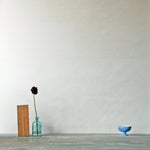 A table with knick knacks stands in front of a wall papered in mottled gold and cream.
