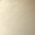 A wall papered in tiles of textured wallpaper in metallic gold and cream.