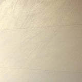 A wall papered in tiles of textured wallpaper in metallic gold and cream.
