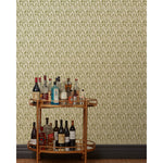 A bronze bar cart in front of a wall papered in an abstract tulip print in a repeating stripe on a sage field.