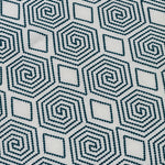 Detail of an embroidered fabric in a geometric spiral design in navy on a cream field. 