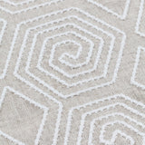 Detail of fabric with a playful embroidered geometric grid print in white on a cream field.