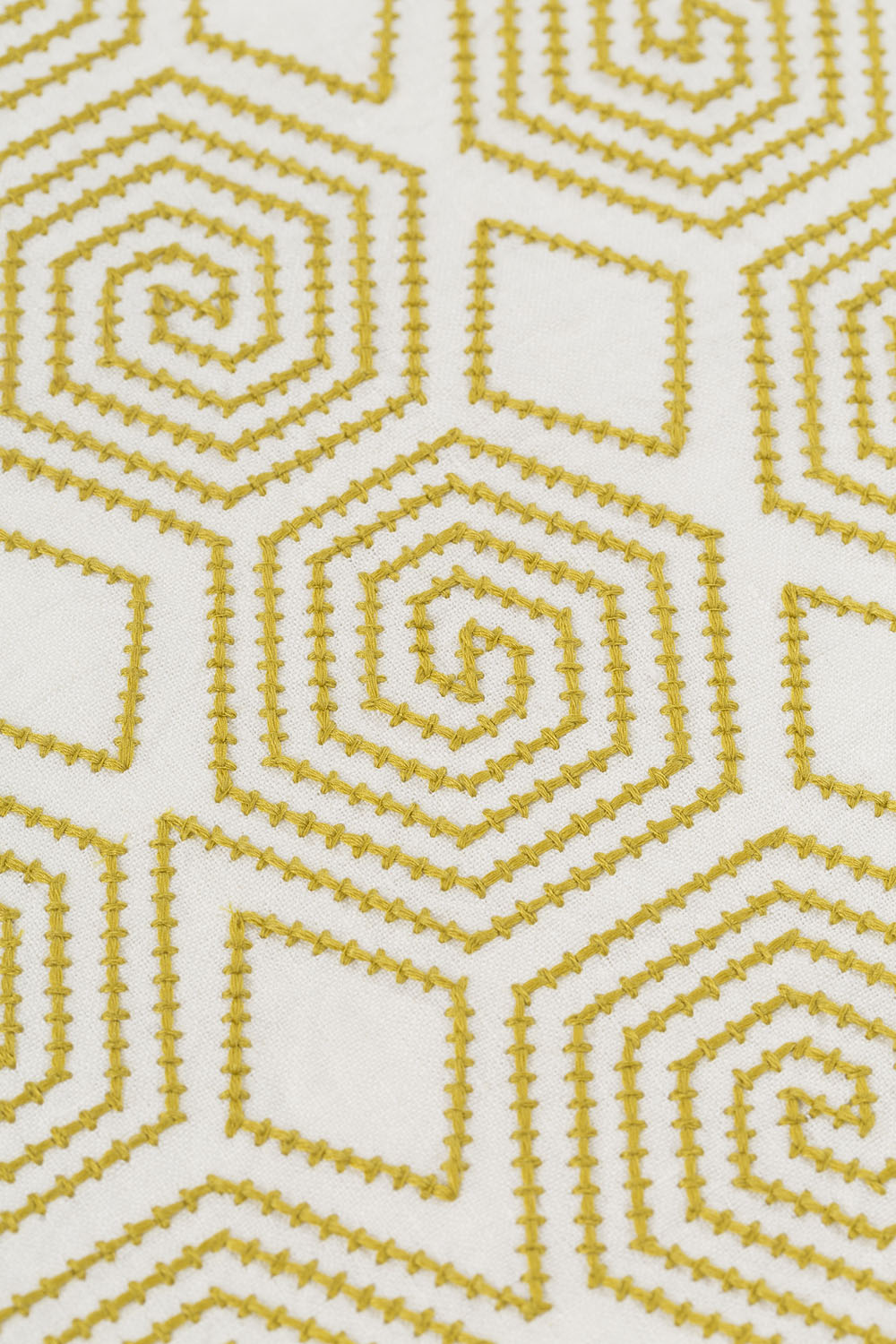 Detail of fabric with a playful embroidered geometric grid print in mustard on a white field.