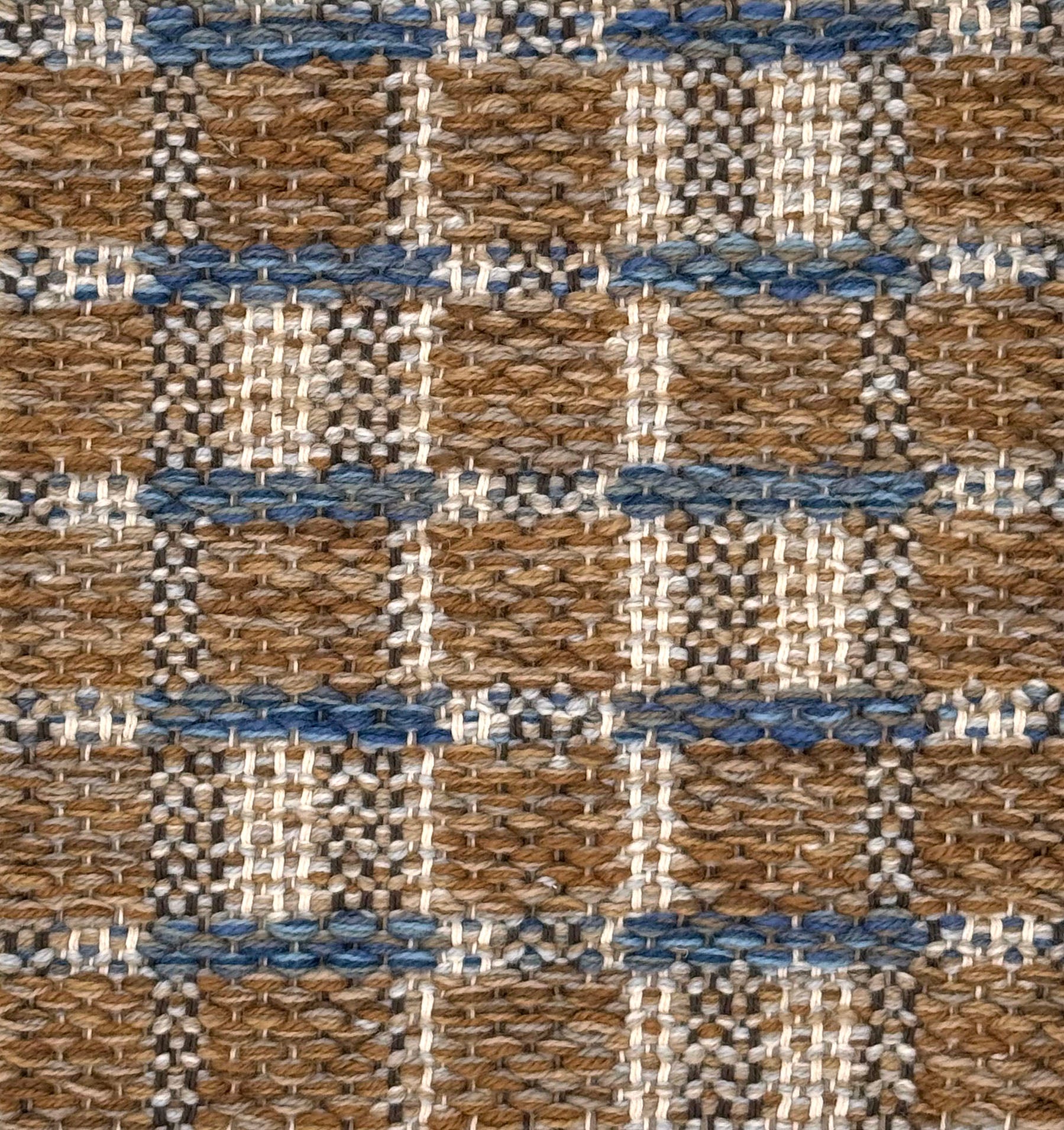 A close-up of a woven rug featuring a brown and beige plaid design with blue accents.