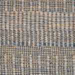 A close-up of a woven rug with a subtle stripe pattern in shades of light blue and tan. 