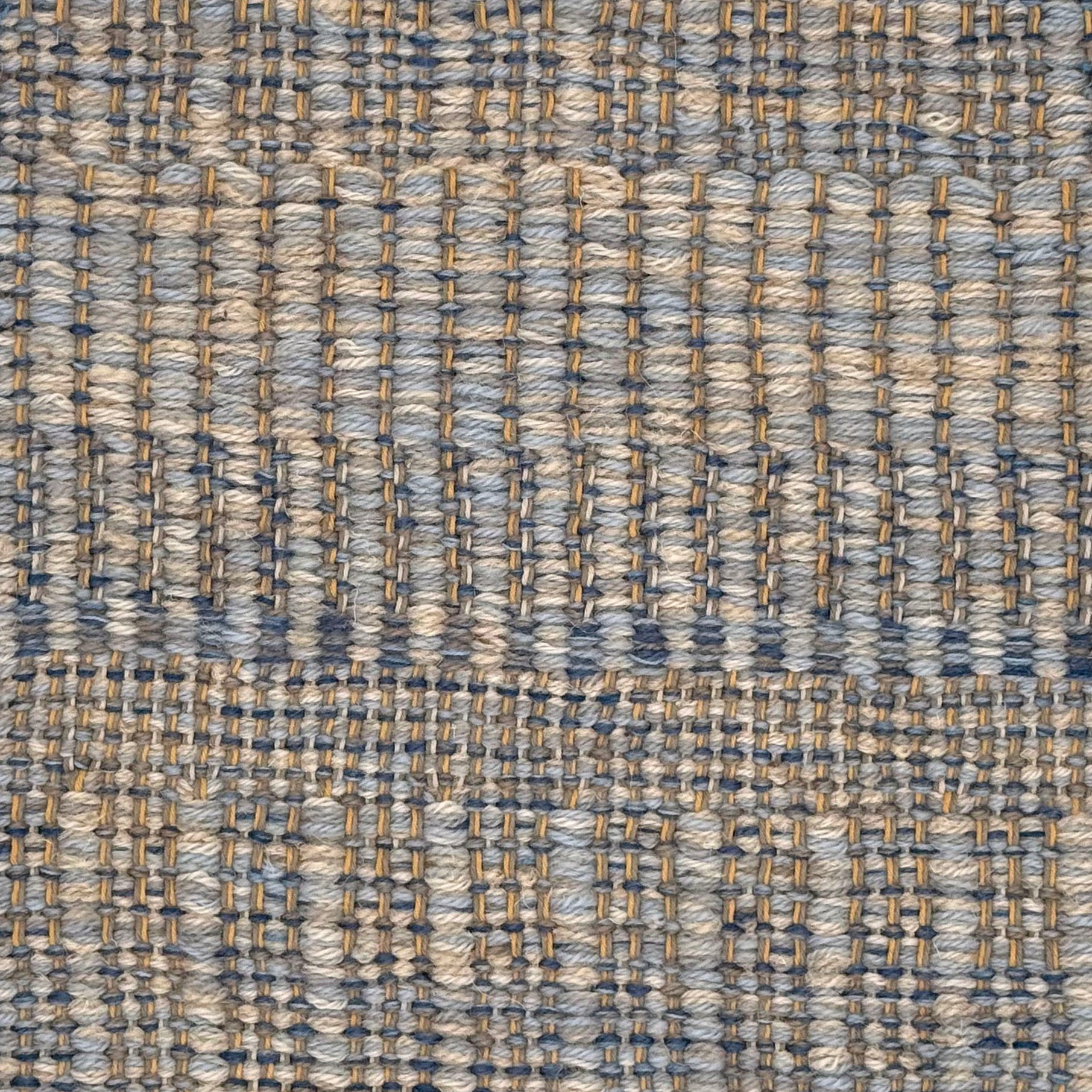 A close-up of a woven rug with a subtle stripe pattern in shades of light blue and tan. 