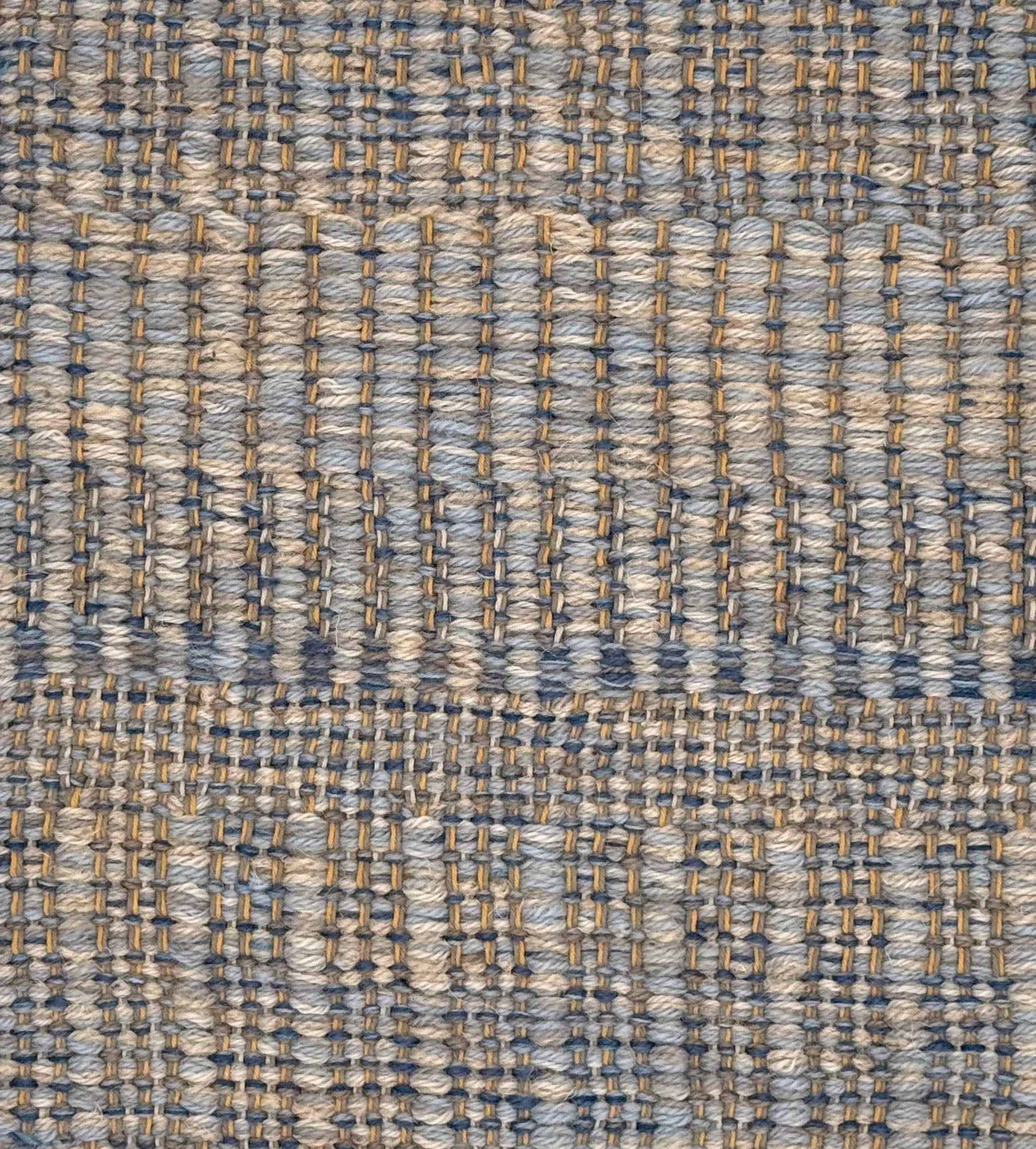 A close-up of a woven rug with a subtle stripe pattern in shades of light blue and tan. 