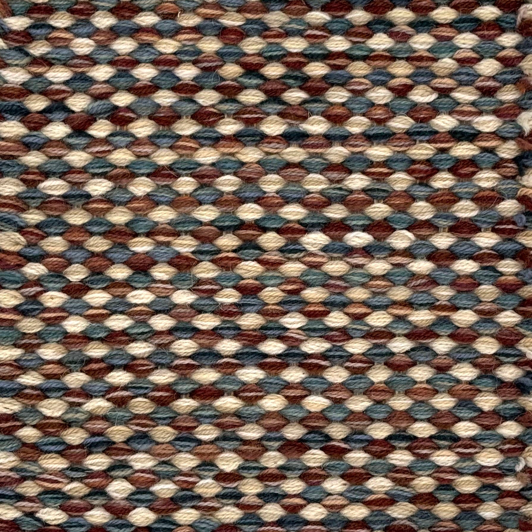 Textured handwoven carpet with a mix of brown, red, cream and blue.