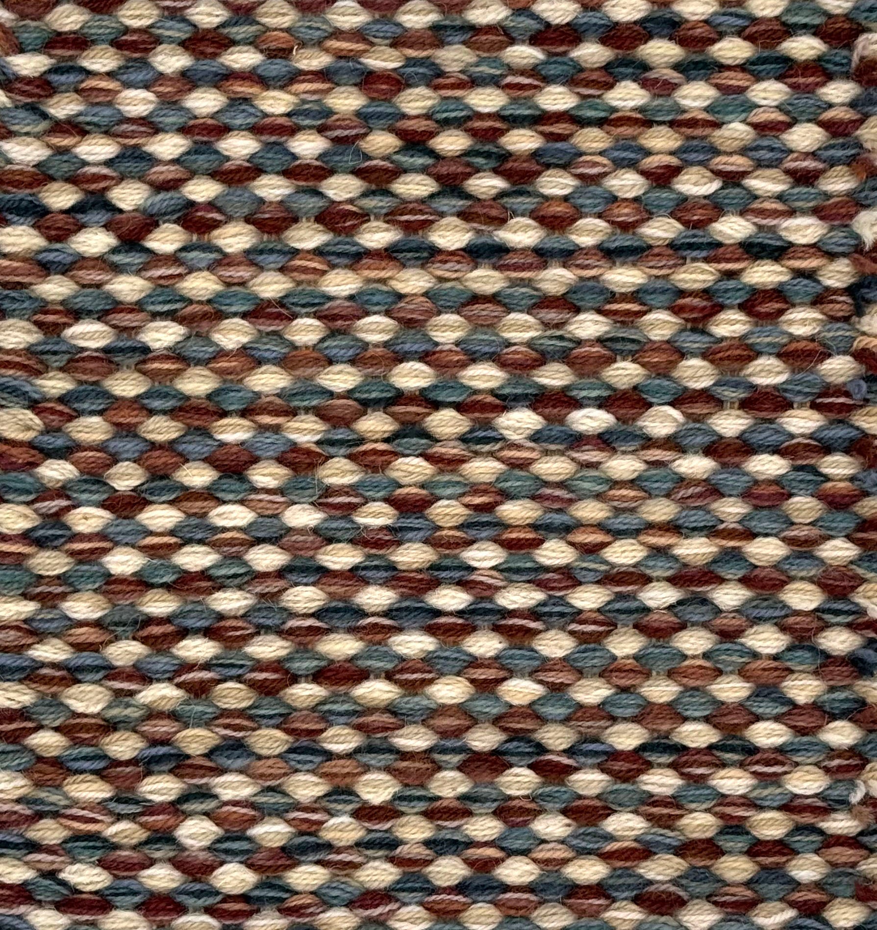 Textured handwoven carpet with a mix of brown, red, cream and blue.