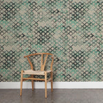 A wooden chair stands in front of a wall papered in a diamond checked pattern in shades of cream, gray and green.