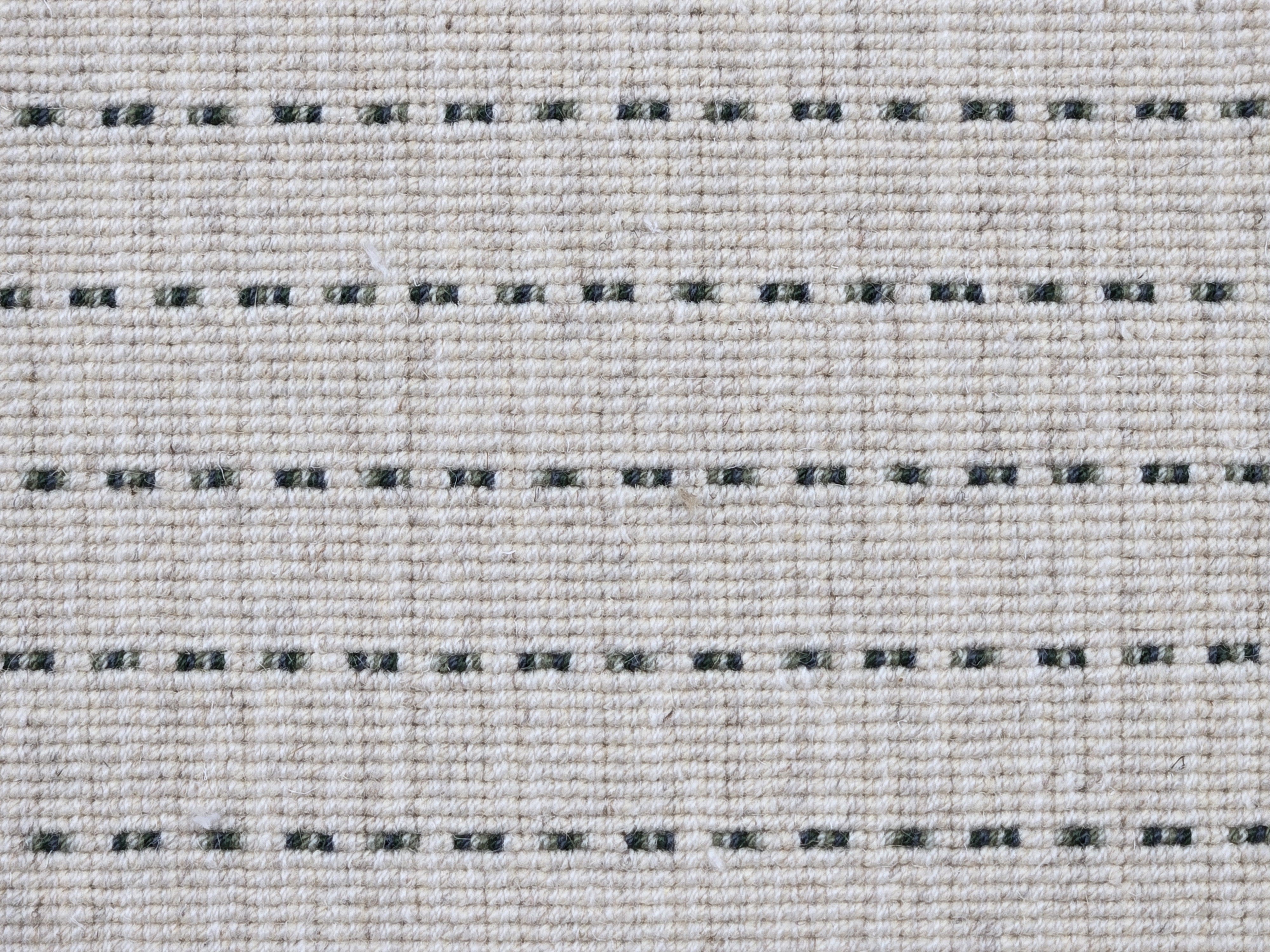 Broadloom carpet detail in a oatmeal field with a forest green stripe.