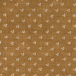 Detail of a linen fabric in a clustered dot pattern in cream on a camel field.