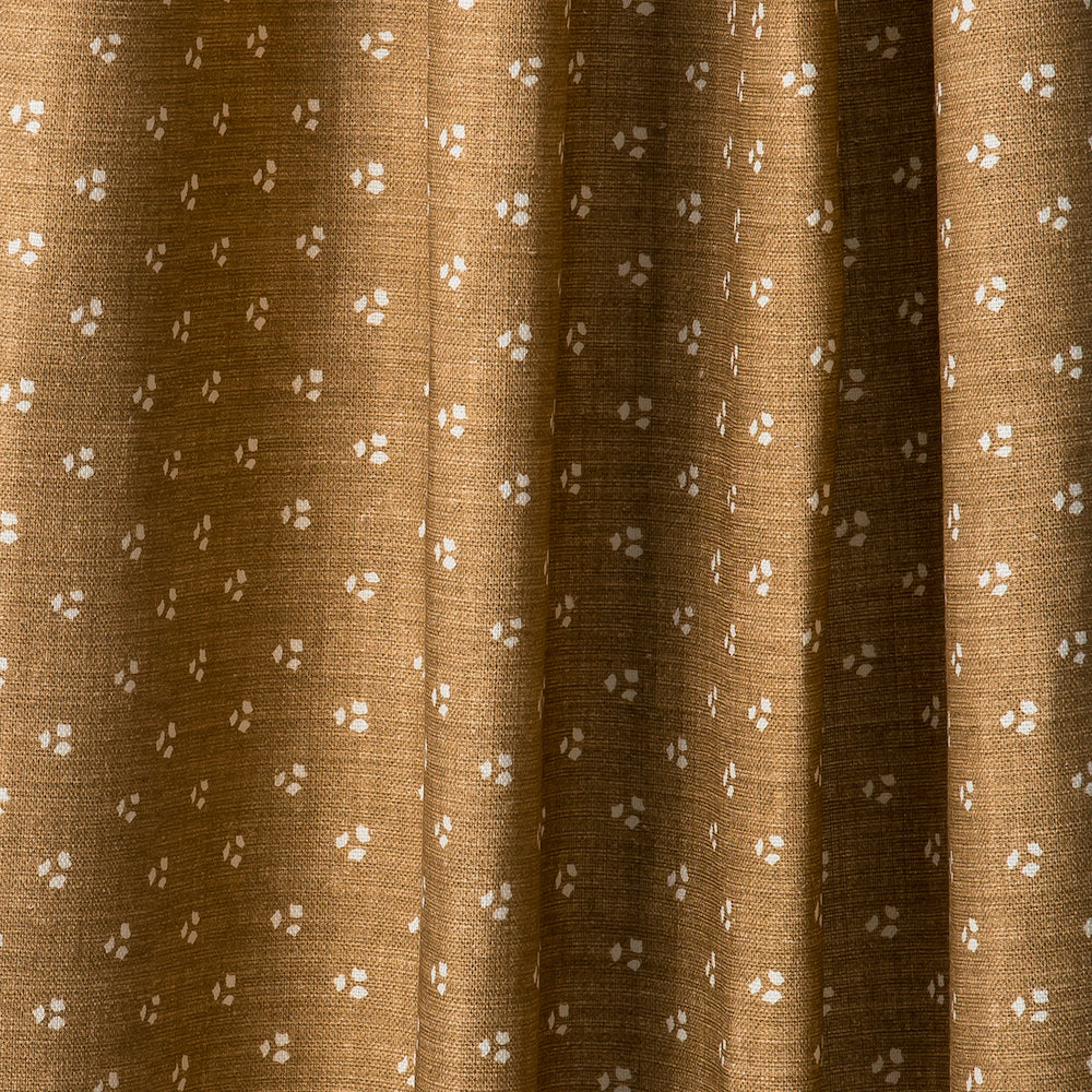 Draped printed fabric in a clustered dot pattern in cream on a camel field.