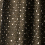 Draped printed fabric in a clustered dot pattern in cream on a dark brown field.