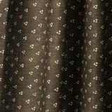 Draped printed fabric in a clustered dot pattern in cream on a dark brown field.