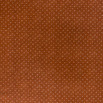 printed linen fabric in a clustered dot pattern in beige on a burnt orange field.