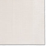 Detail of a hand-painted wallpaper swatch with an irregular grid pattern in beige on a cream field.