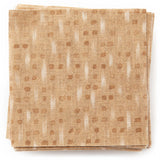 A stack of fabric swatches in a small-scale dot and dash pattern in shades of cream and brown on a bronze field.