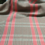 Handwoven fabric gently draped in a subtle window pane plaid in shades of red, pink, brown and cream. 