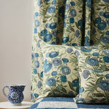 Bedrooms scene with checkerboard quility and pillows in a floral orinted linen in a daisy design in shades of blue with green leaves on a pale cream field.