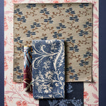 A styled flat-lay of fabric and wallpaper swatches in an array of floral and botanical patterns in blue, beige, pink and cream. 