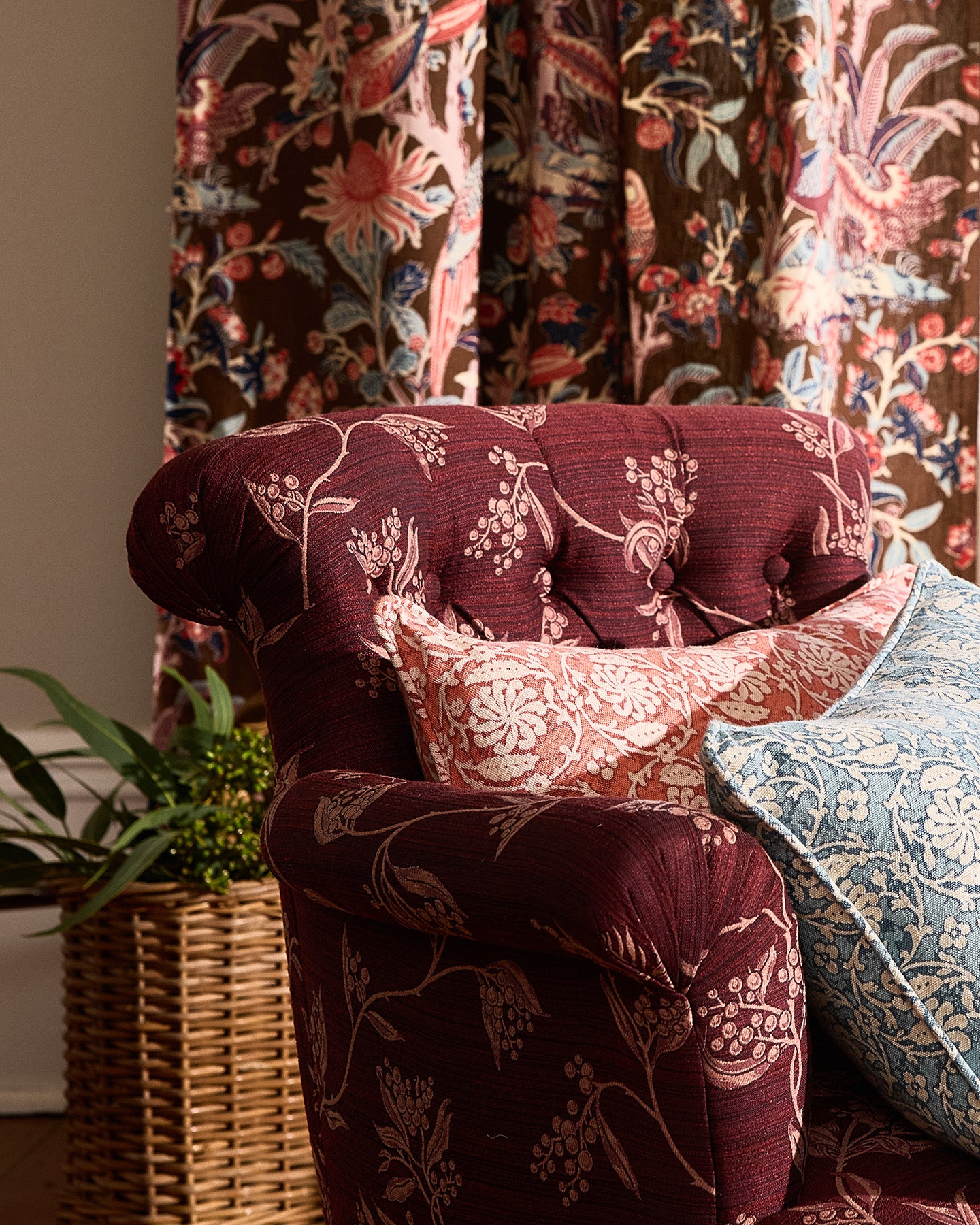 Decorative armchair with floral pattern in a room with floral curtains and a plant.