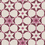 Detail of fabric in a geometric star print in shades of pink and maroon on a cream field.