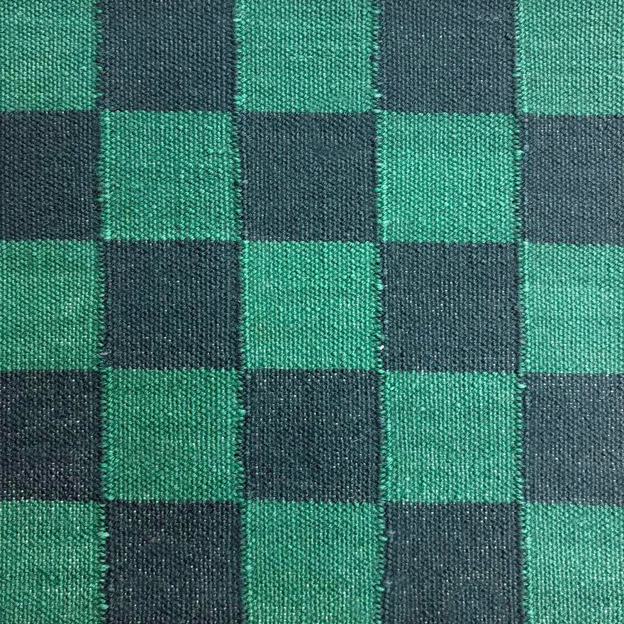 A close-up handwoven rug in a checkerboard pattern in black and green