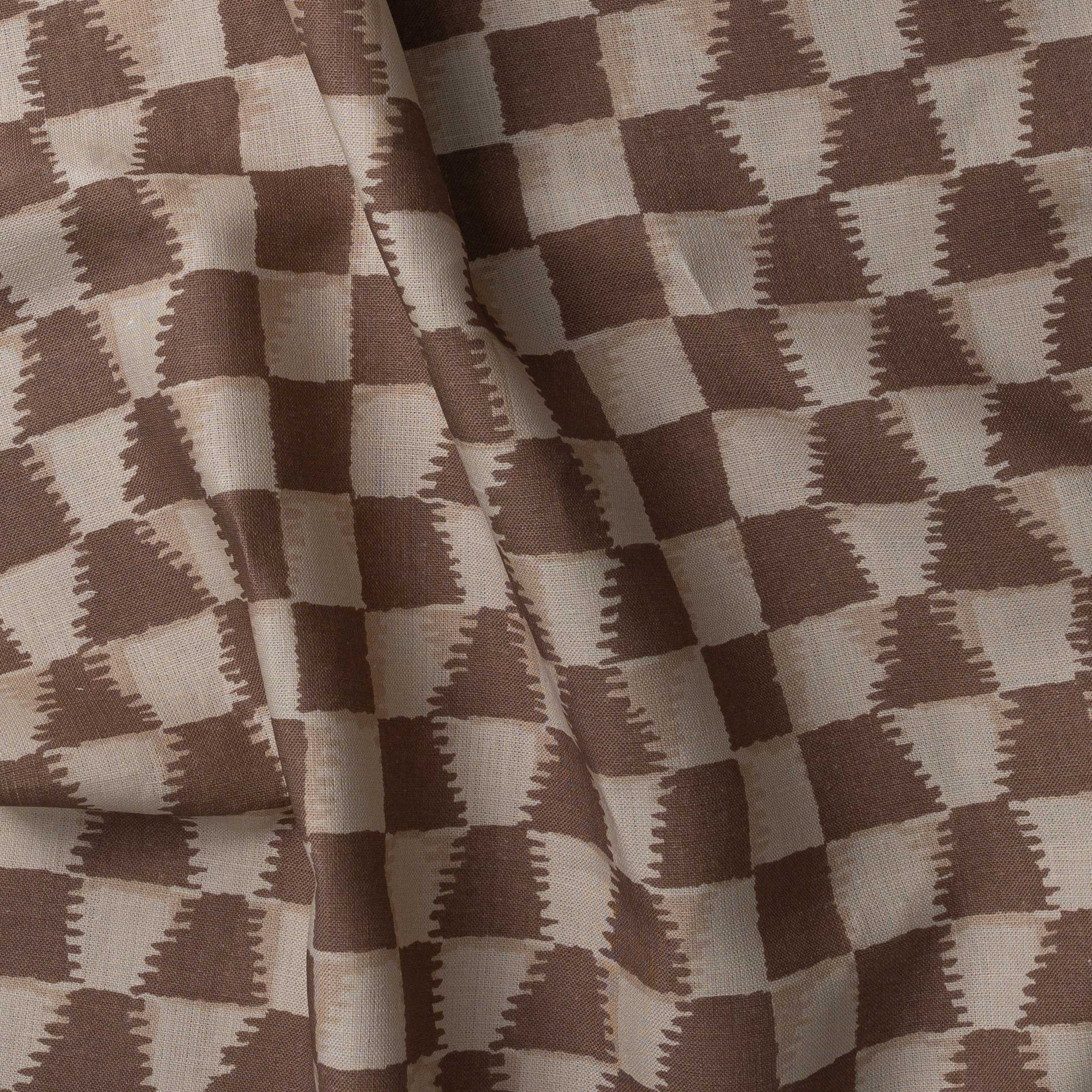 Detail of gently draped printed fabric in a watercolor ikat-inspired checkerboard pattern in tonal warm clay brown. 