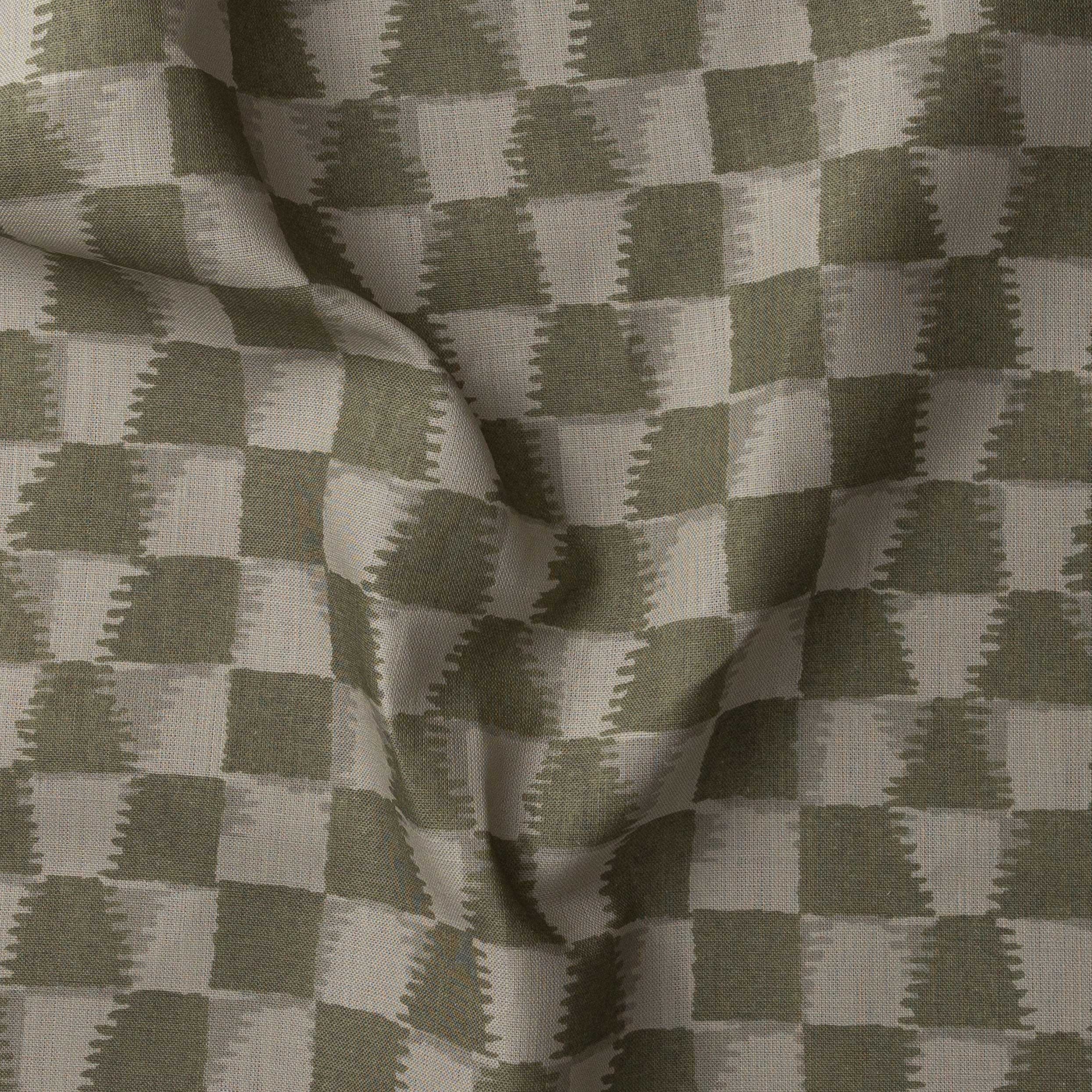 Detail of gently draped printed fabric in a watercolor ikat-inspired checkerboard pattern in tonal muted olive green.