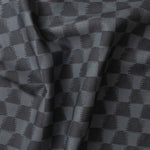 Detail of gently draped printed fabric in a watercolor ikat-inspired checkerboard pattern in tonal navy blue. 