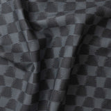 Detail of gently draped printed fabric in a watercolor ikat-inspired checkerboard pattern in tonal navy blue. 