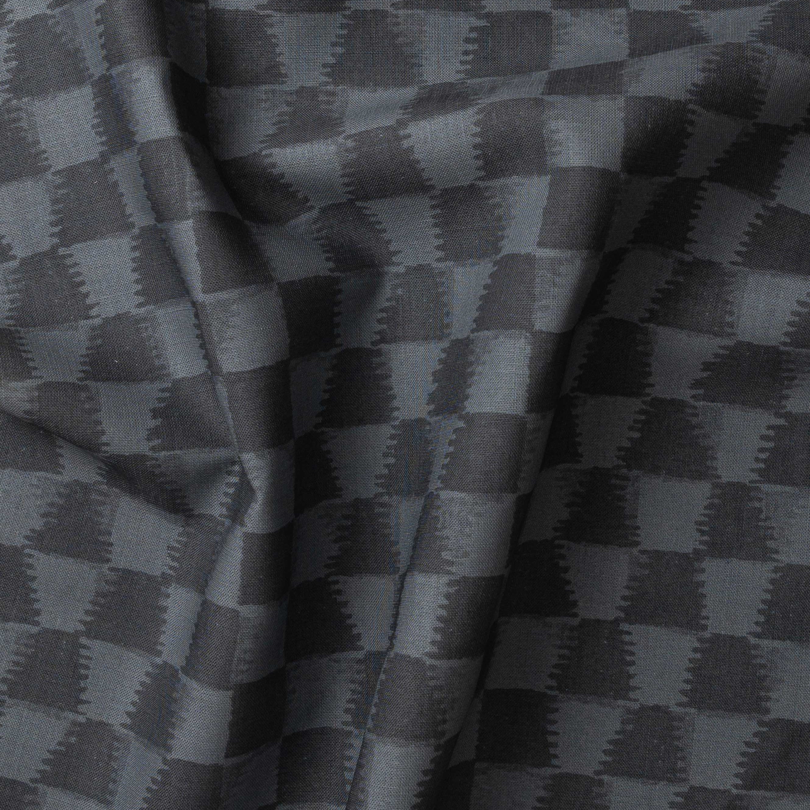 Detail of gently draped printed fabric in a watercolor ikat-inspired checkerboard pattern in tonal navy blue. 