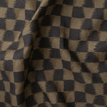 Detail of gently draped printed fabric in a watercolor ikat-inspired checkerboard pattern in muted black and warm tan.