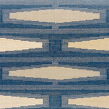 Close up of a handmade flatweave rug with a geometric tiled design in cream and shades of blue. 