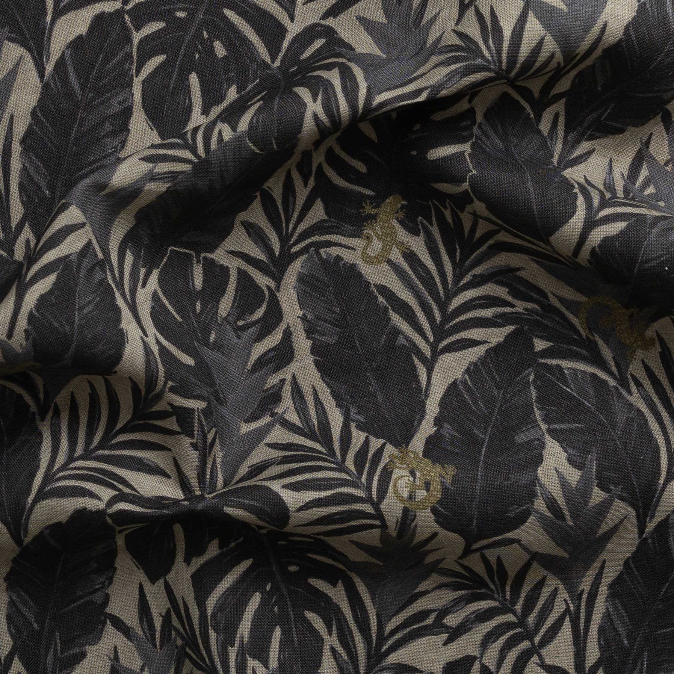 Detail of gently draped printed fabric in a tropical palm frond pattern in faded black and charcoal grey scattered with small tan lizards. 