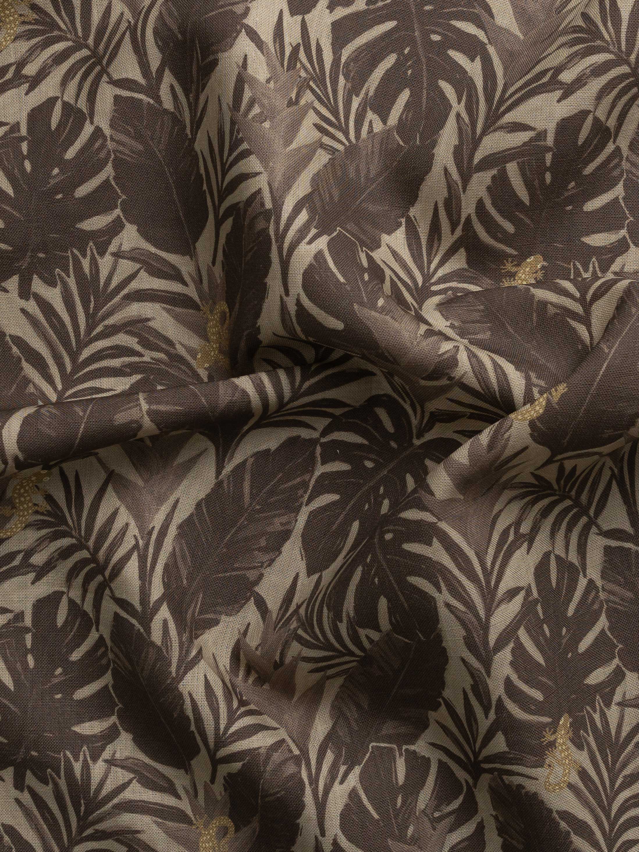 Detail of gently draped printed fabric in a tropical palm frond pattern in tonal brown scattered with small tan lizards. 